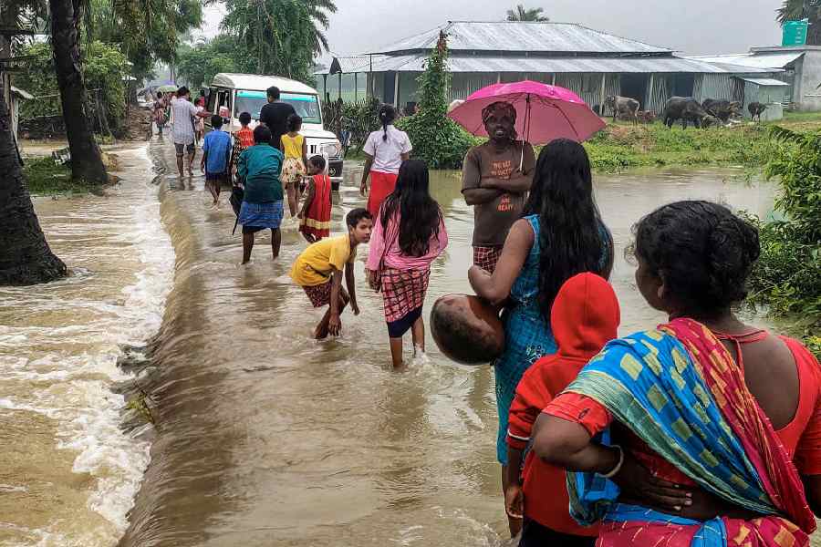 Residents wade through a flooded road in Malda on Sunday