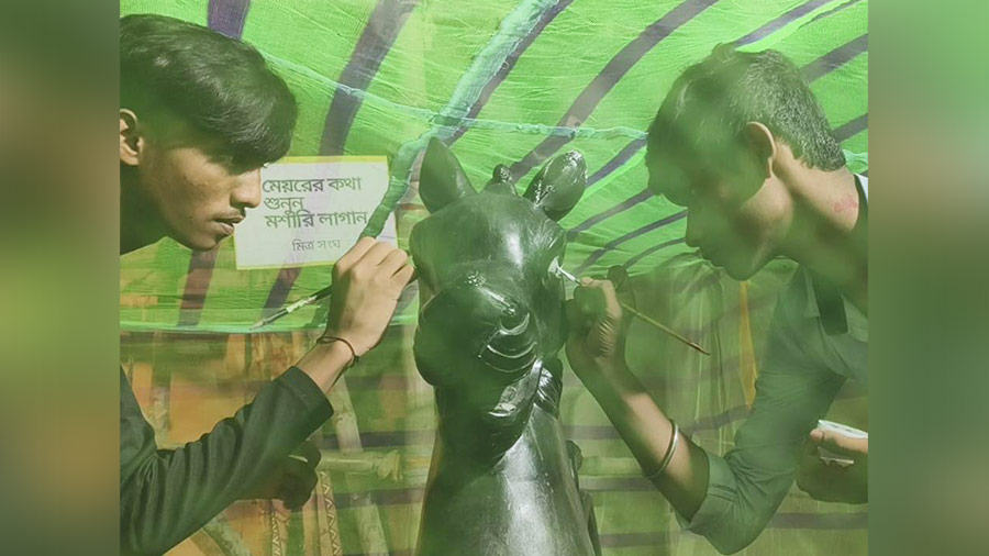 Artists work inside mosquito nets at the Roy Bahadur Road Mitra Sangha Durga Puja pandal