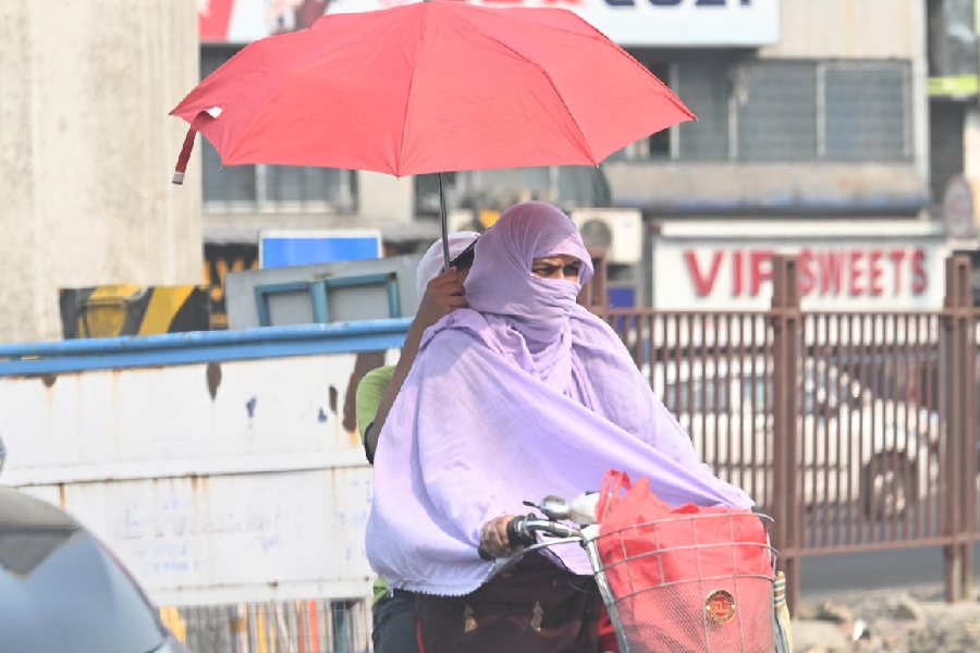 Commuters shield themselves from the sun on Friday afternoon. The day's maximum temperature was 36.7 degrees Celsius, two notches above normal.