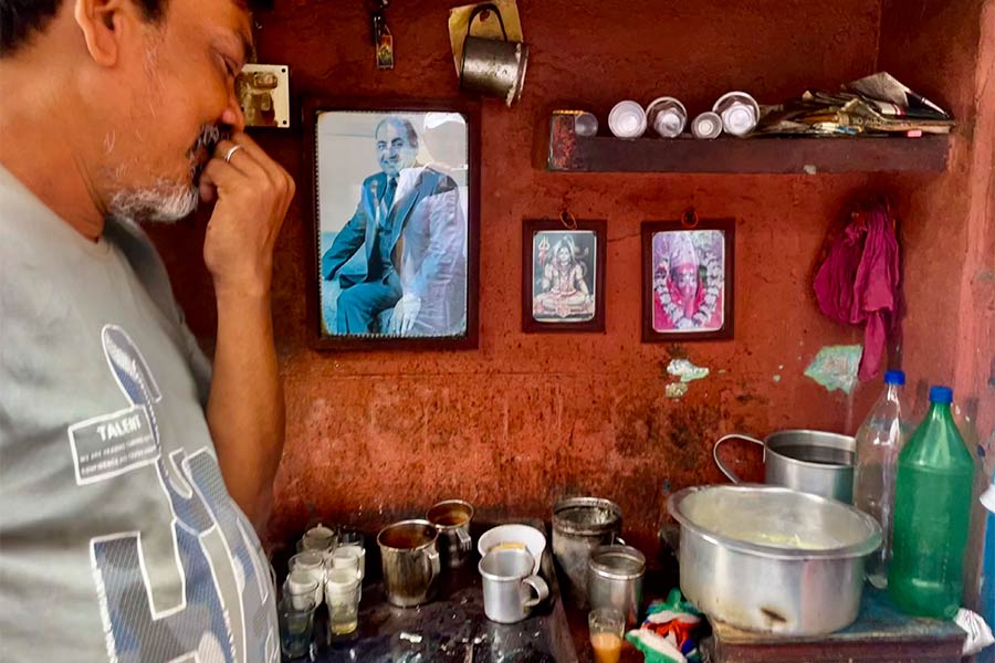 A chaiwala on Premchand Boral Street, whose main wall has a large picture of Rafi and a smaller picture of the bhagwan he worships
