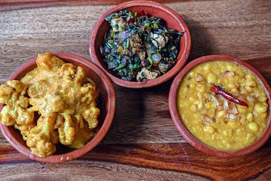 The menu includes classic vegetarian recipes like (centre) Begun Bori Diye Kalmi Shaak Bhaja, (left) Aloo Phoolkopir Roast, Basanti Pulao and Enchorer Dalna. The irresistible pair of (right) Luchi and Chholar Dal adds an extra temptation to the menu