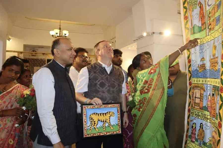  A resident of the Sunderbans explains a life-sized scroll to Niraj Singhal, the head of the forest force in Bengal; Milan Mandal, the DFO of the South 24-Parganas division; and Andrew Fleming, the British deputy high commissioner, at the exhibition on Tuesday.