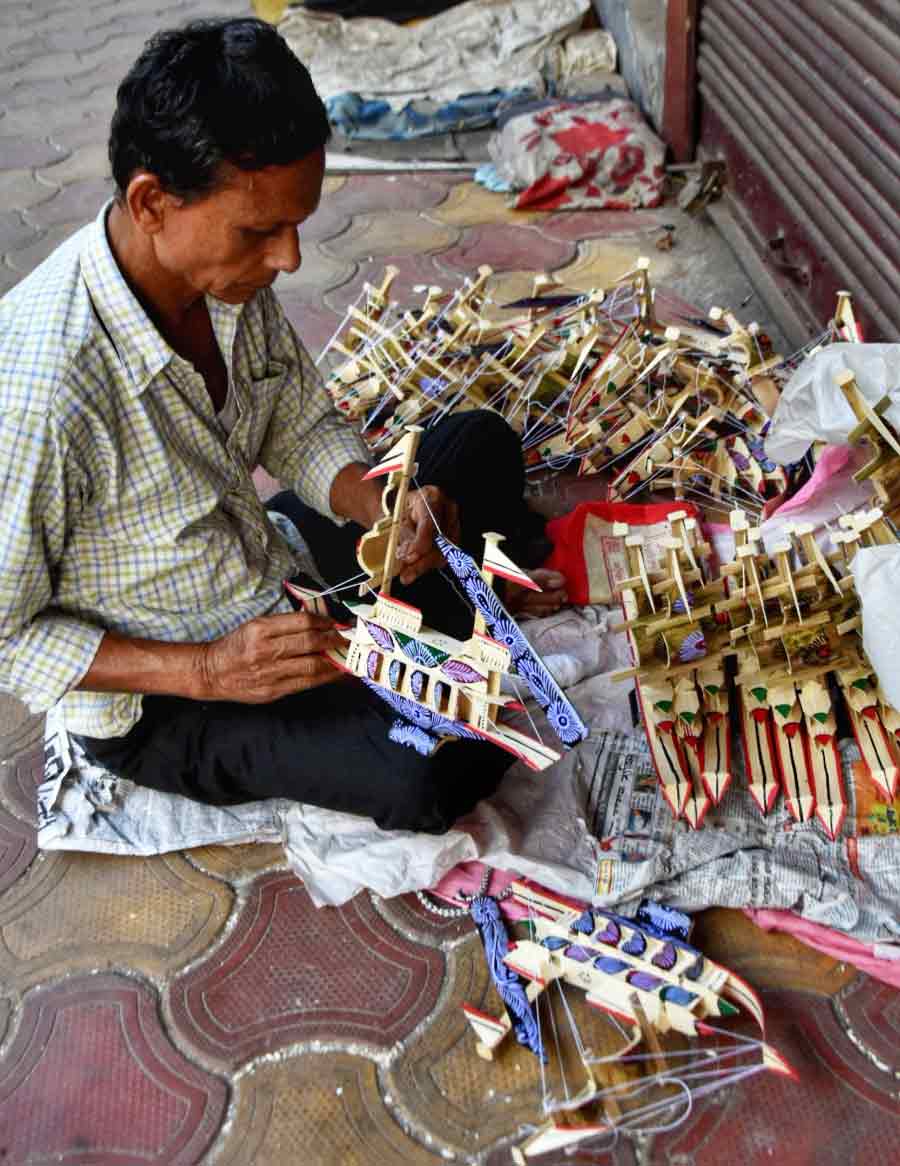 A man selling little toy ships made out of bamboo