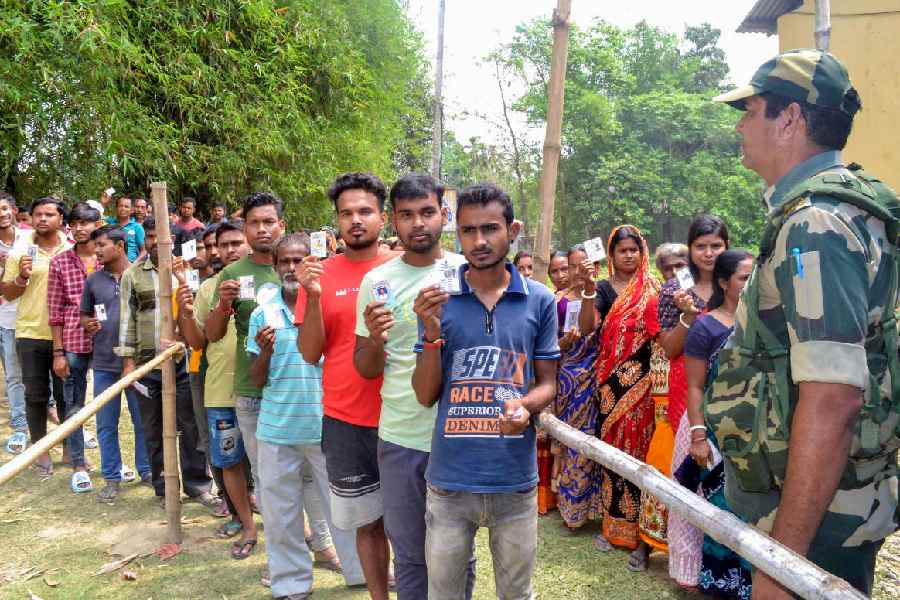 People wait in queues to cast their votes at a polling station during the first phase of Lok Sabha elections, in Cooch Behar district of West Bengal