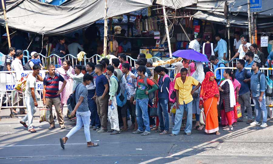 Passengers wait for buses under the shade of the foot overbridge near Sealdah flyover 