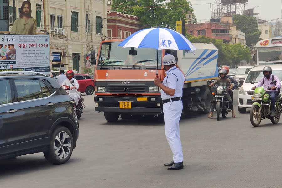 A traffic police personnel puts his new umbrella to best use immediately. 