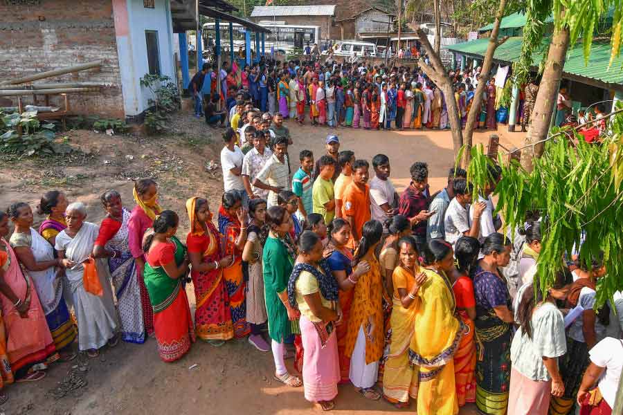 People wait to cast their votes for the second phase of Lok Sabha elections, in Morigaon district, Friday, April 26, 2024.