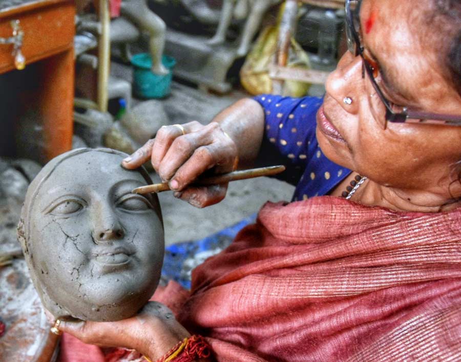 Potter China Pal works on the face of a Durga idol at her studio in Kumartuli