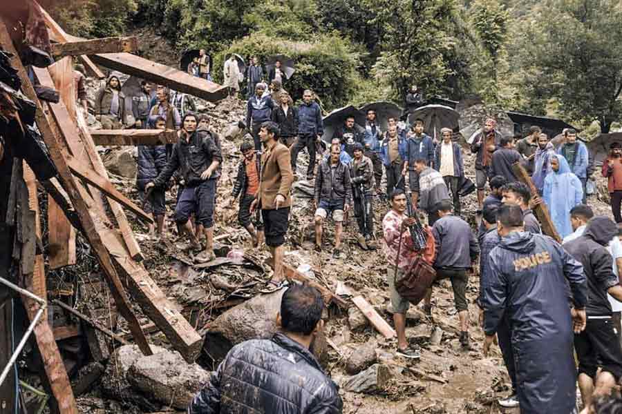 Officials and locals stand near a washed-away area at Rajvan village after a cloudburst, Mandi district, Thursday, Aug. 1, 2024.