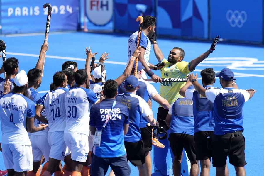 Goalkeeper Parattu Reveendran Sreejesh, in yellow jersey, reacts as India's players celebrate after winning