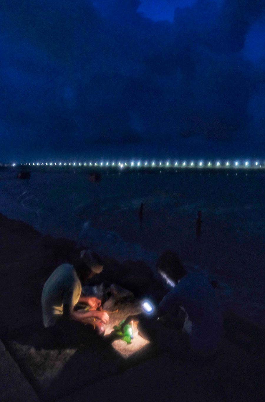 Fishermen fix floaters to their nets before venturing out in the sea at night