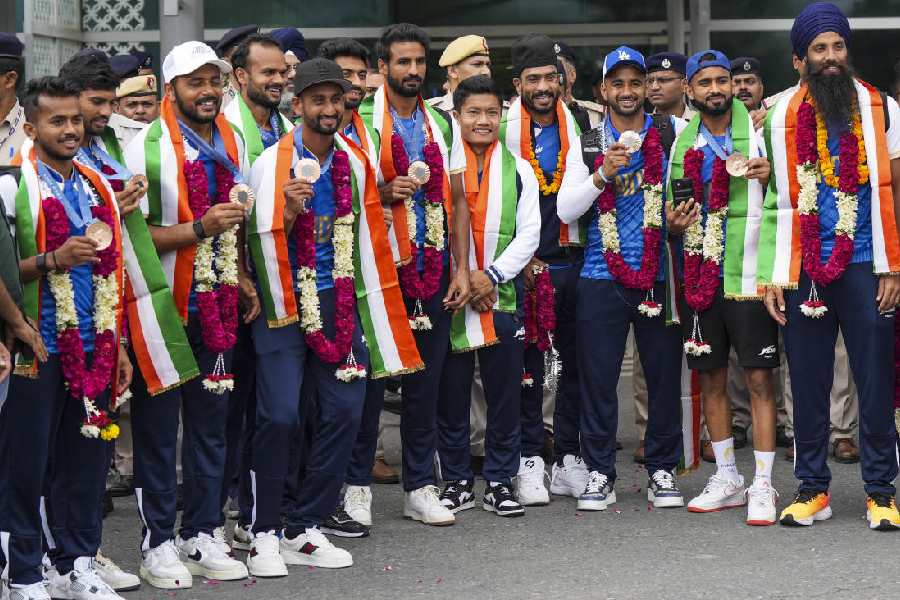 The bronze medal-winning India hockey team pose for photographs on arrival in New Delhi on Saturday.