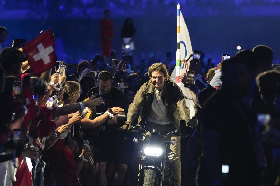 Tom Cruise rides a motorbike with the Olympic flag attached during the 2024 Summer Olympics closing ceremony at the Stade de France, Sunday, Aug. 11, 2024, in Saint-Denis, France