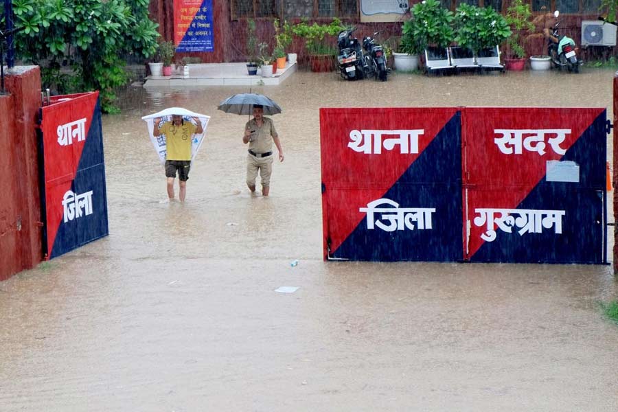 Police personnel at the waterlogged Sadar police station amid monsoon rain, in Gurugram