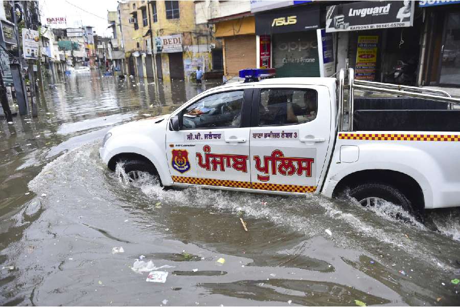 A car moves on a waterlogged road after heavy monsoon rainfall, in Jalandhar
