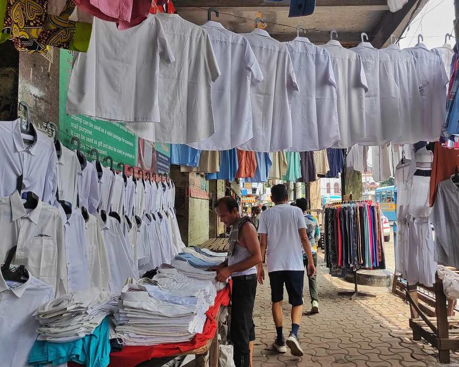 Rows of  white shirts on sale on a pavement at Esplanade East