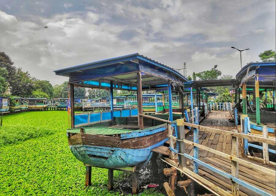 Ramshackle boats tied to broken wooden jetty at the Patuli Floating Market