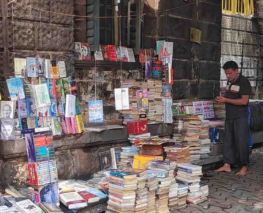 A bookseller arranges books for sale on a sidewalk in central Kolkata