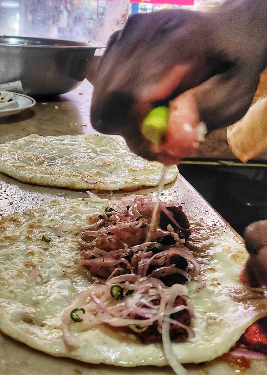 How was the Kolkata roll invented? It was born from the hustle of Dalhousie’s ‘office para’ lunch-time crowds during colonial rule. Nizam’s wrapped kebabs, onions, and a dash of lime in a crispy paratha — it cut the queues, made the dish convenient for those on the go, and was perfect for the British clientele who were reluctant to soil their fingers!
