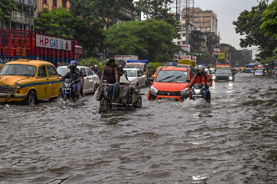 Commuters wade through a waterlogged road amid rains, in Calcutta, Saturday, Aug 24, 2024.