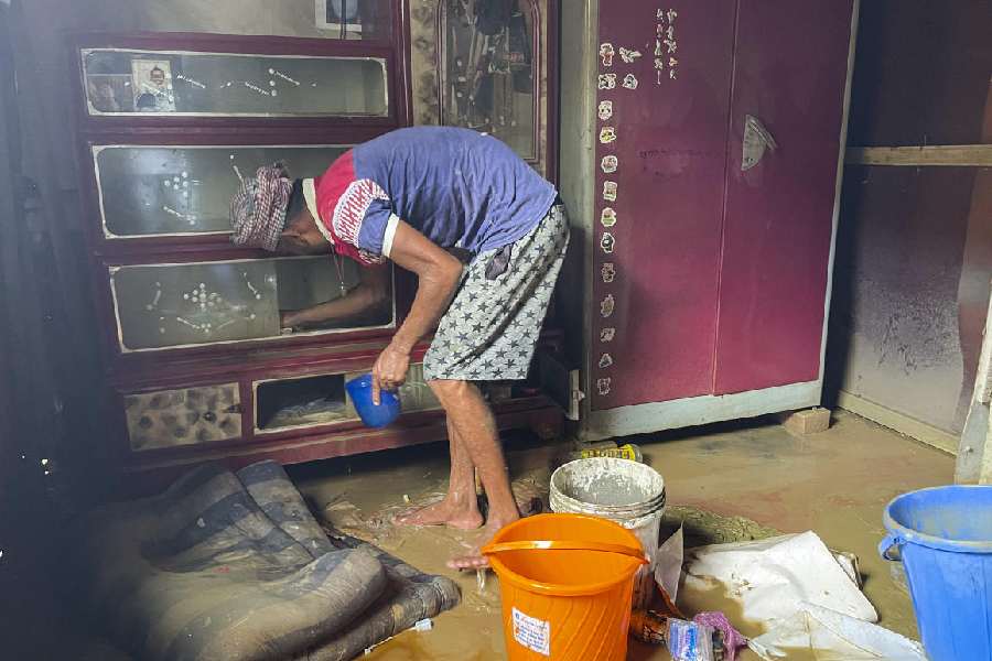 A man cleans his house after it was waterlogged following heavy rains, in Agartala, Saturday, Aug. 24, 2024.