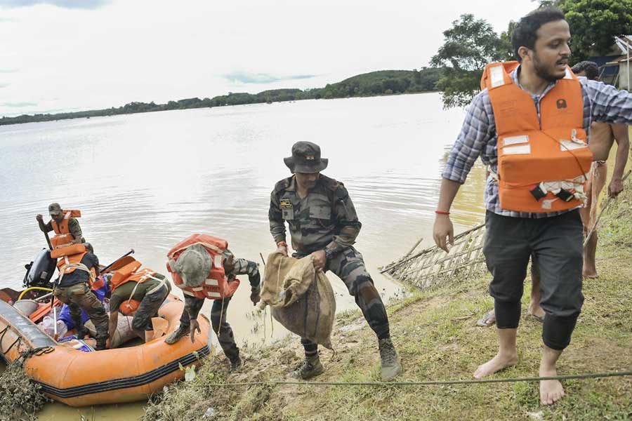 Security personnel bring food supplies for distribution at relief camps at Amarpur area, during a rescue and relief operation at flood-affected area, in Gomati district, Monday, Aug. 26, 2024.