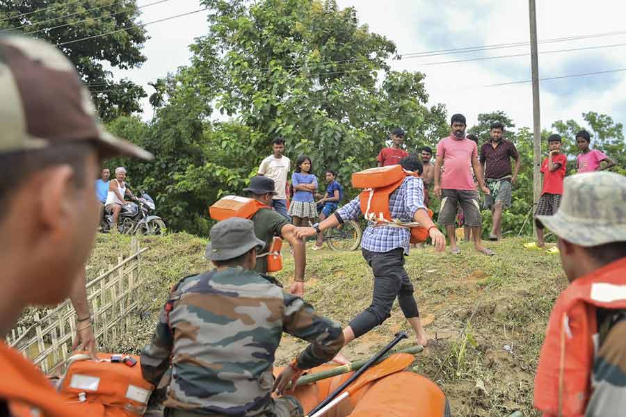 Security personnel and others distribute food supplies during a rescue and relief operation at flood-affected Amarpur area, in Gomati district, Monday, Aug. 26, 2024.