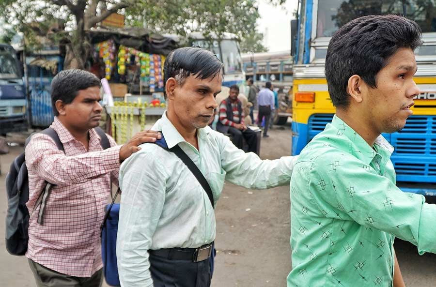 Partially sightless people cross a road with the help of one other on World Disability Day at Esplanade on Tuesday morning