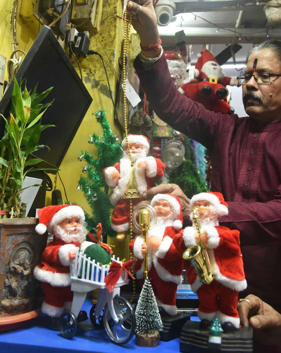 A fancy Santa Claus on sale at Old China Bazar Street in Burrabazar plays the saxophone, pushes the trolley and distributes chocolates and gifts