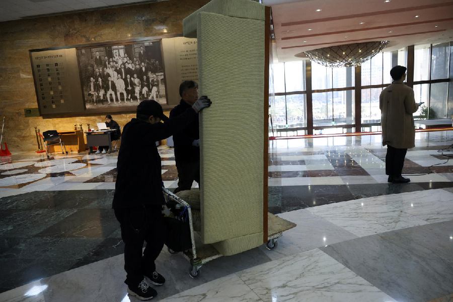 Workers remove a piece of furniture used for barricading when military forces broke into the National Assembly building after South Korean President Yoon Suk Yeol declared martial law. 