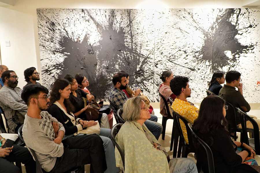 The audience listened attentively to the panellists. To their left is an artwork by Kingshuk Sarkar titled ‘Barood’ (2024)