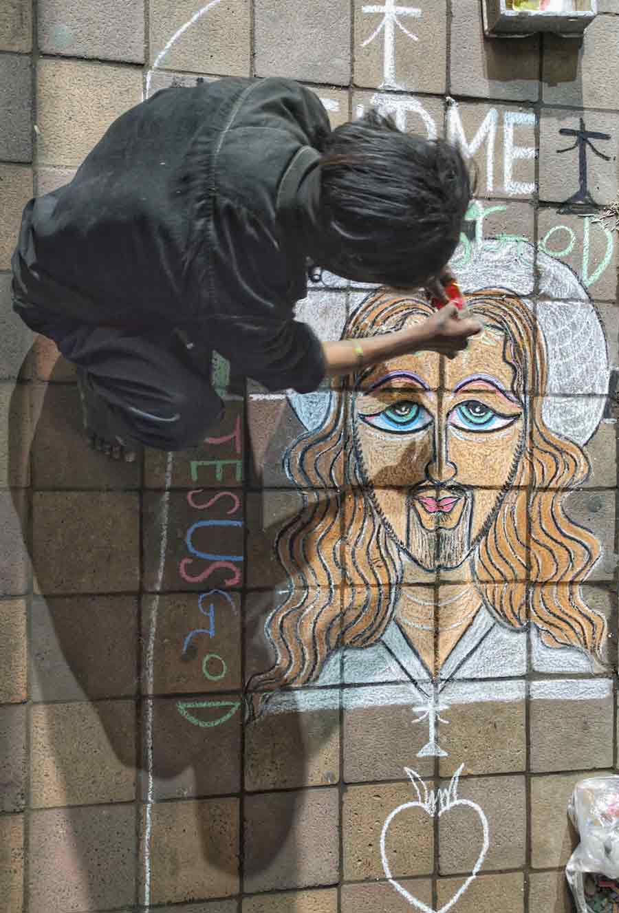 With barely two weeks left for Christmas,  a street artist sketches a portrait of Jesus Christ on a pavement in Kolkata