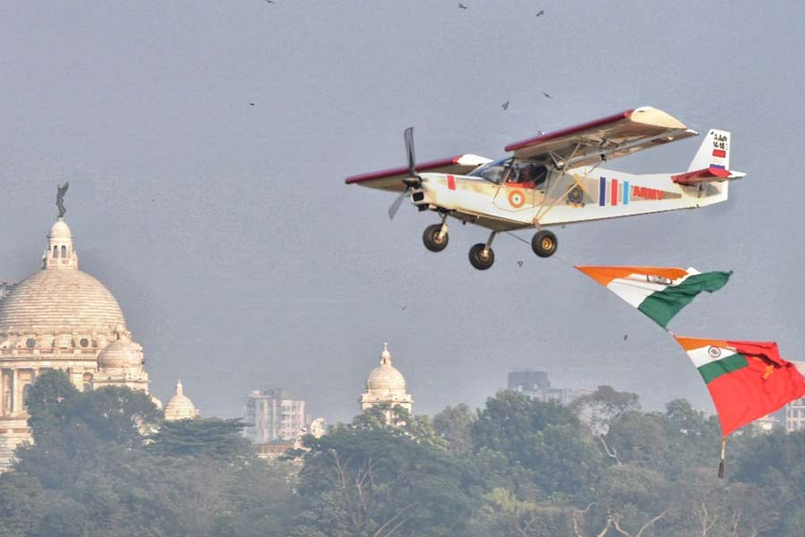 An aircraft flies over the Brigade Parade Grounds with the Victoria Memorial Hall in the background
