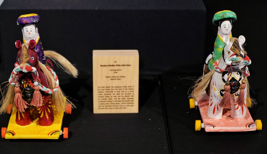The paper-made versions of Ryukyu Hariko: Chin-chin Uma by Toyonaga Morito showcase the riding style of the royal family of the Ryukyu Kingdom. The dolls and the horses are placed on wheeled bases and dressed in colourful attires