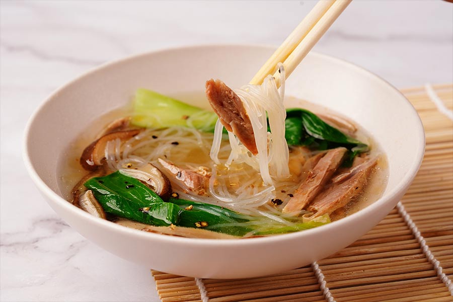 Start with a bowl of hot and hearty Duck Meat Noodle Soup. This non-spicy clear soup has glass noodles, succulent dusk meat, shitake mushrooms and pakchoi