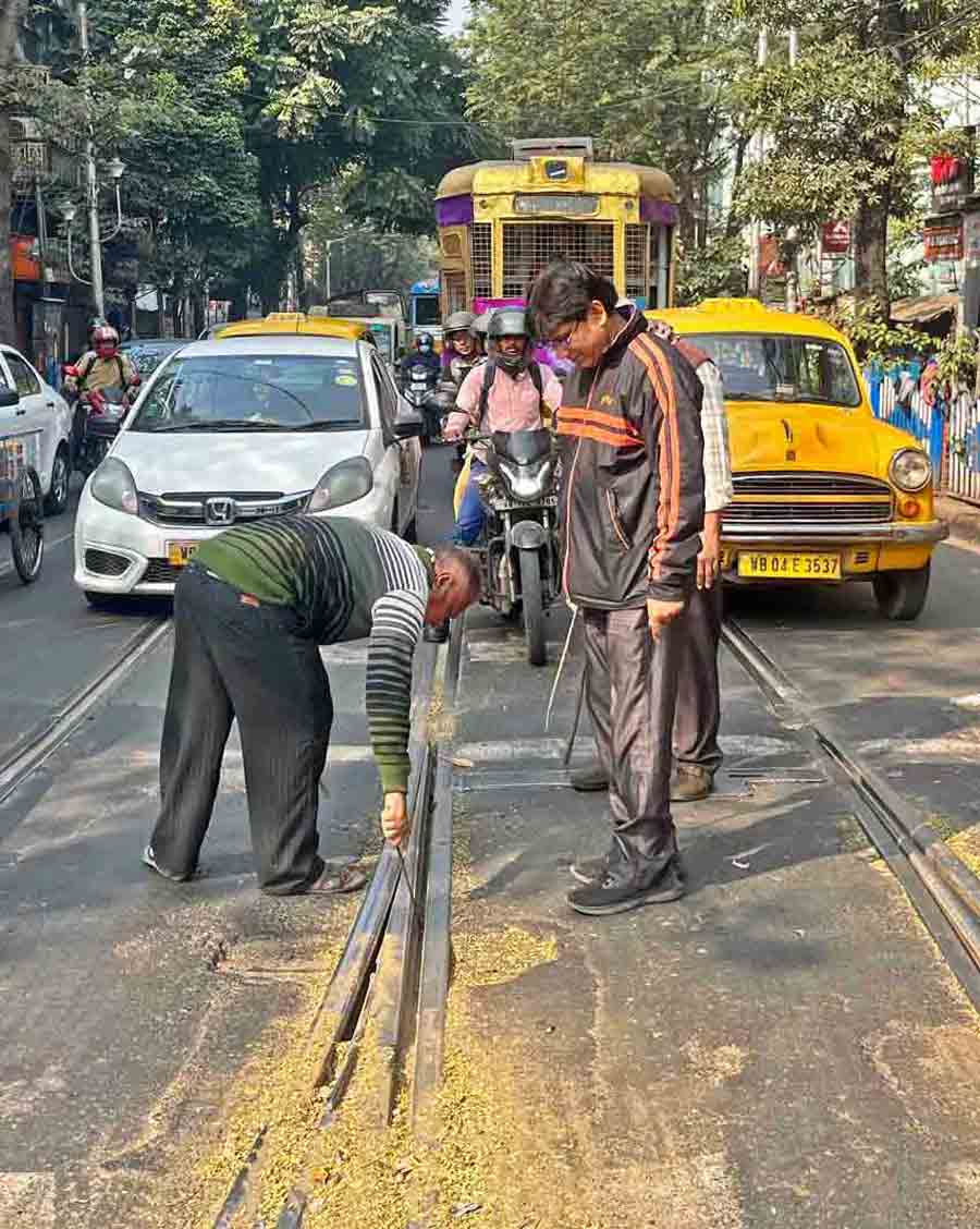 Tramways employees clean up tracks at the Wellington crossing on Lenin Sarani