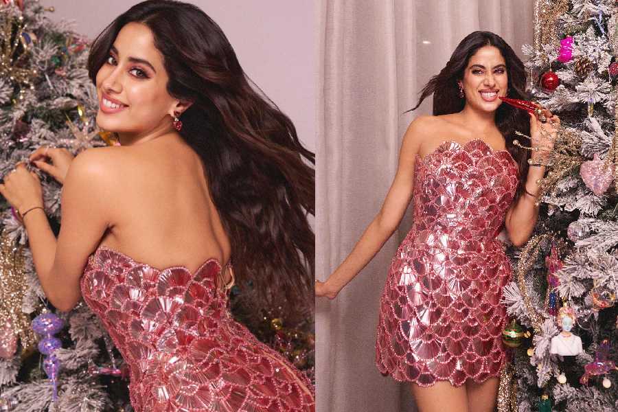 Clad in a metallic pink mini dress, Janhvi Kapoor posed in front of a silver-spangled Christmas tree. 