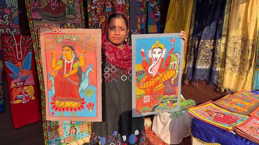 A shopkeeper displays hand-painted wall scrolls at the Nayagram Patachitra Mela on Saturday. It will continue till January 3, 2025