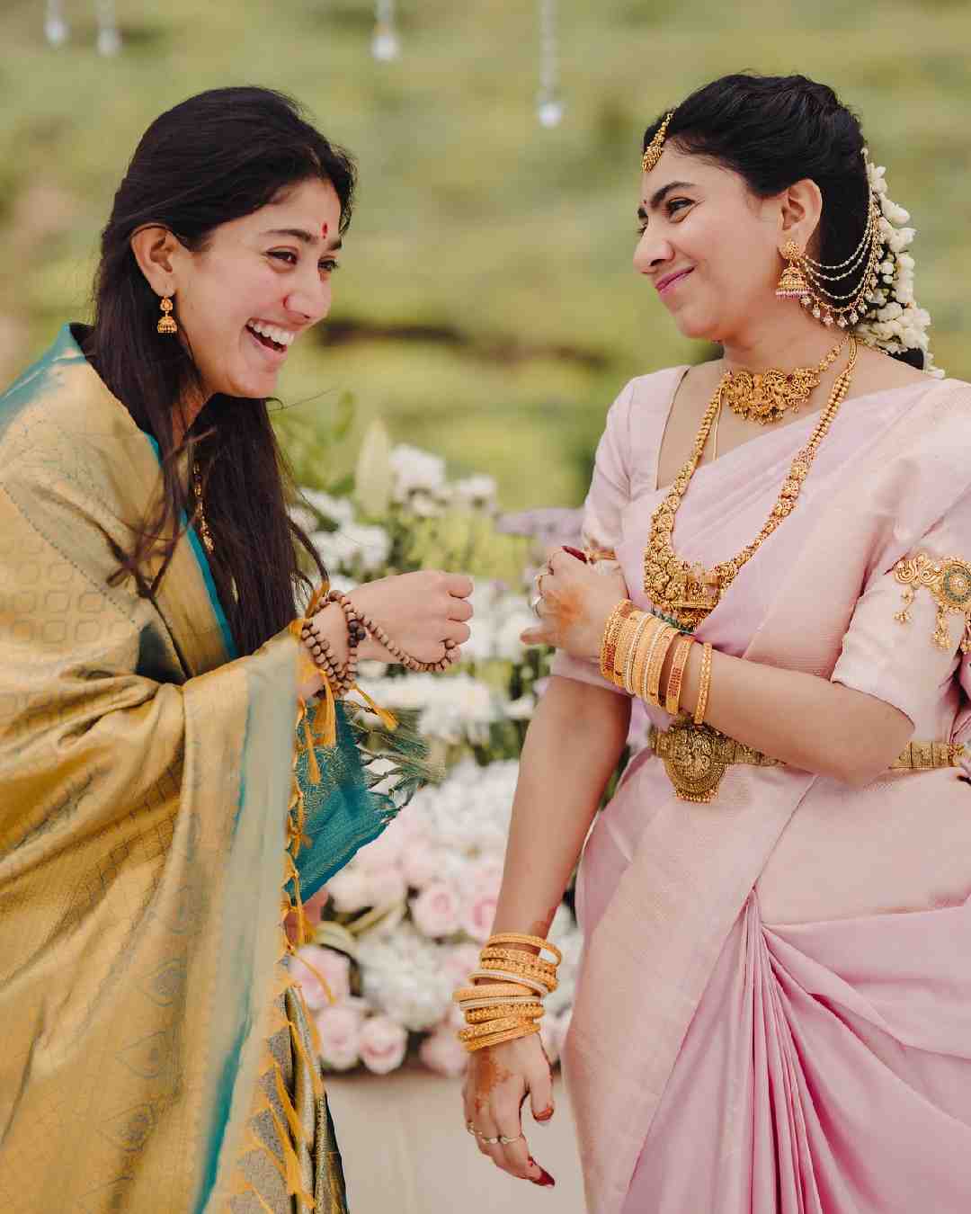 A candid picture captures Pallavi and Pooja laughing their hearts out during the festivities. While Pallavi looks gorgeous in a gold-and-turquoise sari, Pooja stuns in a light pink sari. 