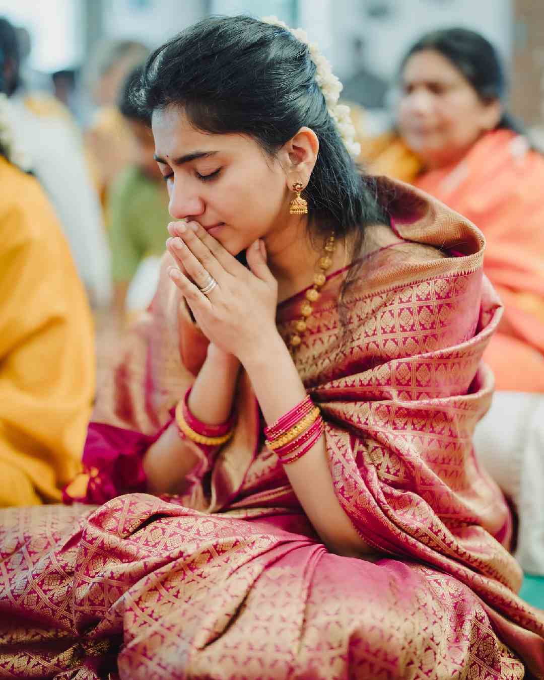 Pallavi joins her hands in prayer in the photo. The Amaran actress looks beautiful in a crimson-and-gold sari. Gold toned earrings, necklaces and a stack of matching bangles complete her look.  