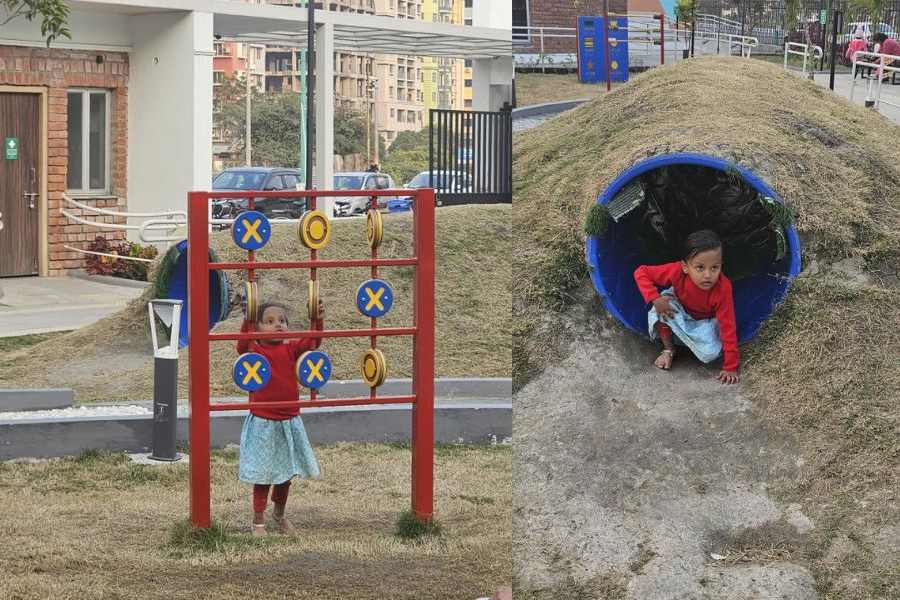 A child plays with noughts and crosses gear at the park and (right) crawls out of a tunnel mound.