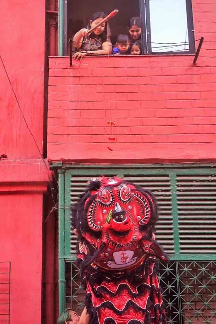 A young lady at Bow Barracks shows off her skill in making the Dragon dance right from their window above the street