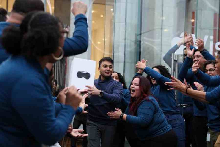 Apple employees cheer as a customer carries a box with Apple's Vision Pro headset at the Apple Fifth Avenue store in Manhattan in New York City