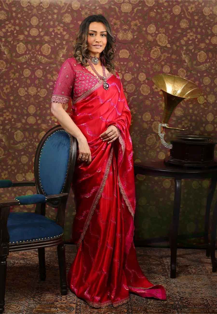 Namrata Shirodkar exuded vintage vibes in a red satin silk sari adorned with pink floral details. A red-and-golden bridal blouse and matching stone jewellery complemented the look.  