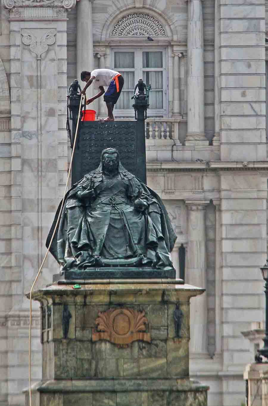 A worker cleans the statue of Queen Victoria on Wednesday  