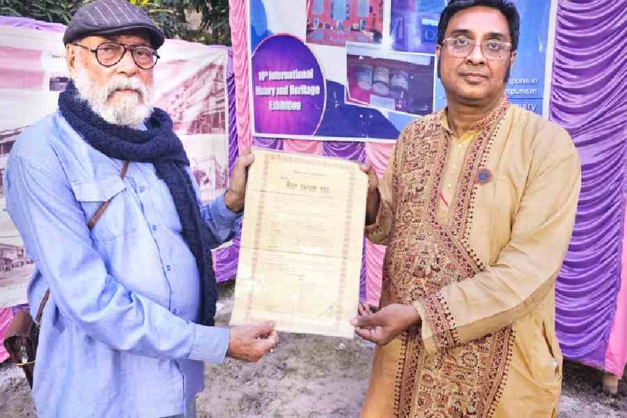 Alok Kumar Mukherjee hands over a document bearing Netaji Subhas Chandra Bose’s signature to Devarshi Roy Choudhuri of the Sabarna Roy Choudhuri Paribar Parishad at the Barisha Boro Bari in Behala on Saturday