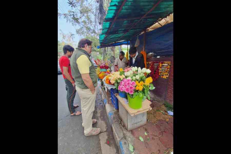 Customers buy flowers from a stall at Kwality More