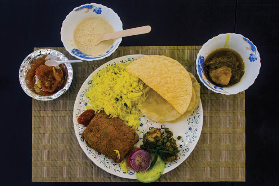 A typical thali at Khelat Ghosh Mansion serving luchis, alur dom, salad, fish fry, pulao, mutton curry, papad, chutney and payesh