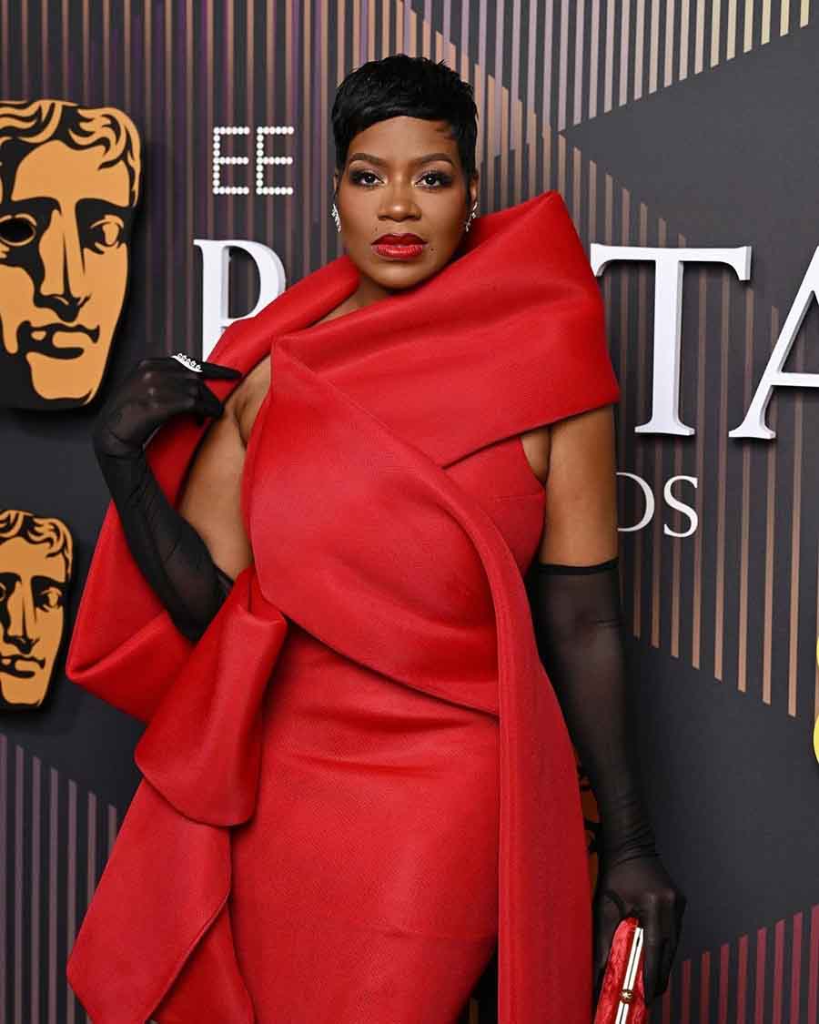 The Color Purple actress Fantasia Taylor made her BAFTA debut in a red gown featuring an oversized shawl collar, with opera gloves.