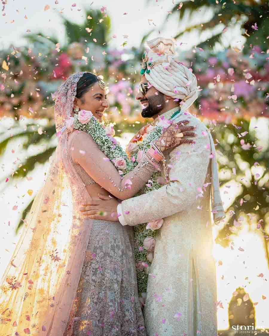 The couple posed for a picture against a backdrop of palm trees dotted with confetti.  